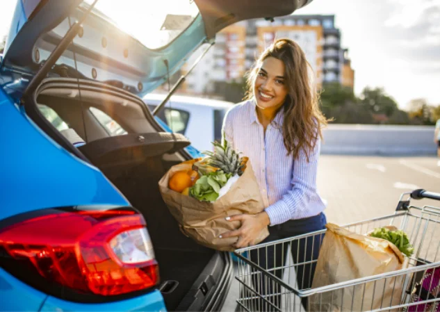 A picture of woman smiling besides a car